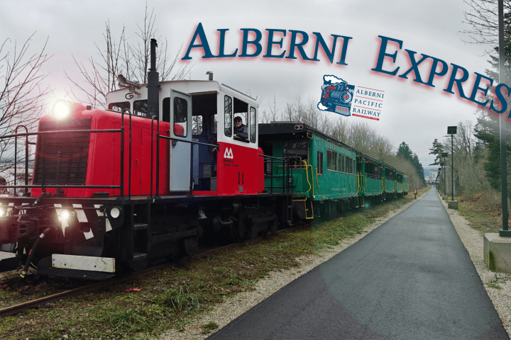 Red and white train with green carriages labeled 'Alberni Express' on a cloudy day.
