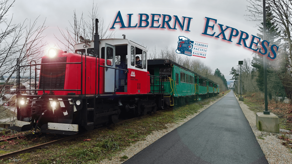 Red and white train with green carriages labeled 'Alberni Express' on a cloudy day.