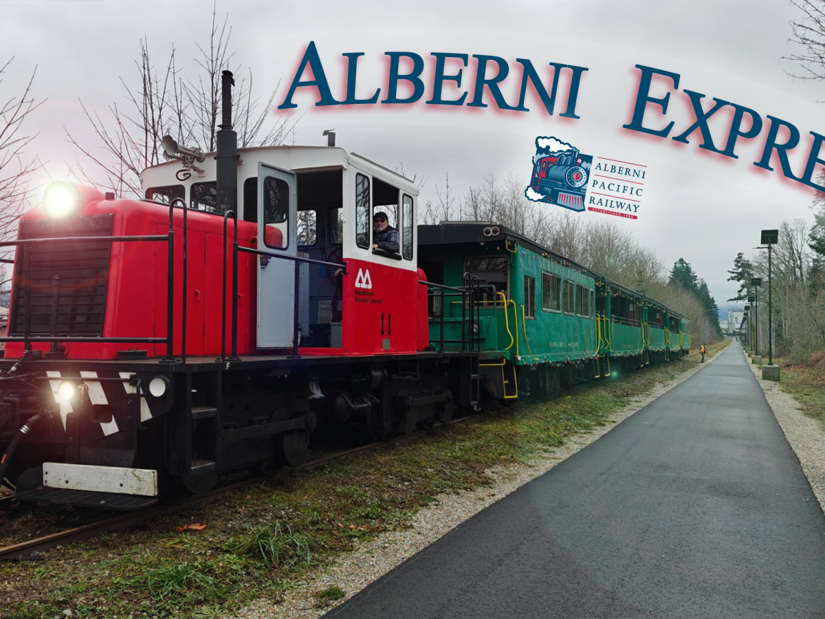 Red and white train with green carriages labeled 'Alberni Express' on a cloudy day.